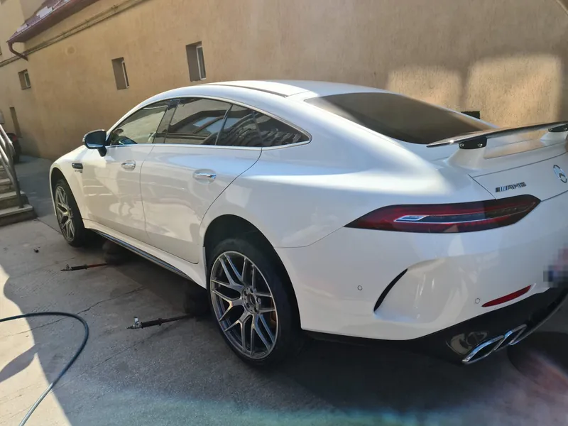 Mercedes-AMG GT cu patru uși, alb, văzut din spate, cu jante gri