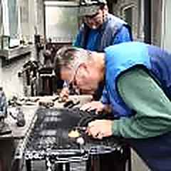 Doi mecanici lipesc un radiator pe bancul de lucru