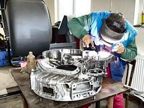 Mecanic cu mască de sudură care sudează în argon o carcasă din aluminiu