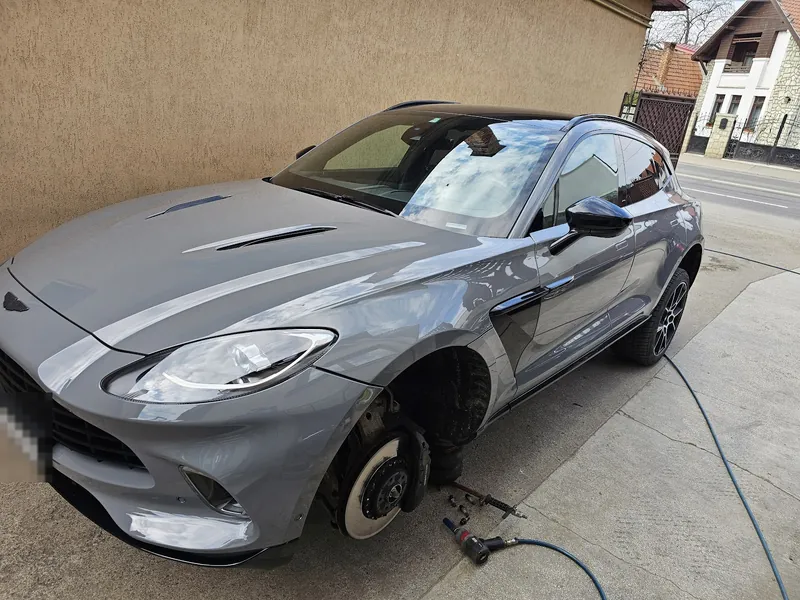Aston Martin DBX gri, cu roata din față demontată și discul de frână la vedere