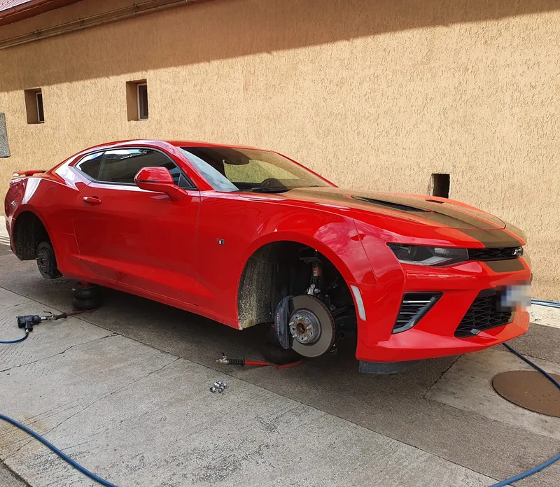 Chevrolet Camaro roșu cu roțile demontate, pe perne