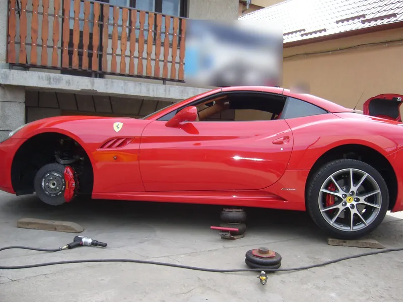 Ferrari California roșu, din profil, cu roata din față demontată