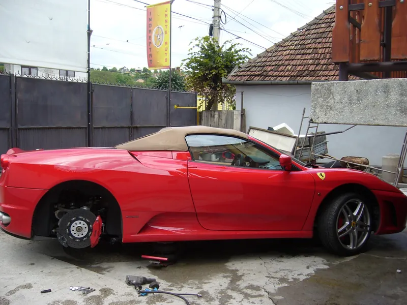 Ferrari F430 Spider roșu, din profil, cu roata din spate demontată și discul ceramic la vedere