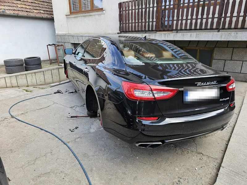 Maserati Quattroporte negru văzut din spate, cu roata din spate demontată